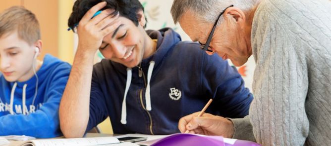 Eldre lærer hjelper ung gutt.